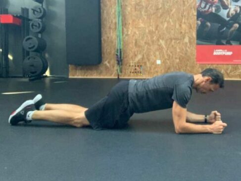 Homme en planche sur coudes et genoux